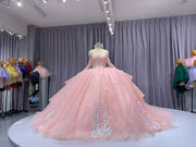 Pink quinceañera dress with corset bodice, illusion sleeves, and princess silhouette skirt.