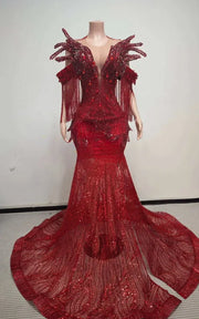 Ruby red beaded mermaid gown with sculptural chest fin details, sequin fringe off-the-shoulder sleeves, and floor-length illusion train