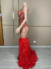 Luxury sleeveless prom dress with shining red rhinestones and a dramatic feather skirt. Ruby glamorous formal gown.