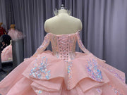 Pink quinceañera dress with corset bodice, illusion sleeves, and princess silhouette skirt.
