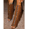 Brown fringe knee high boots with cross straps and stiletto heels.