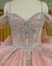 Blush pink glitter quinceañera ball gown with silver appliqués and corset bodice.