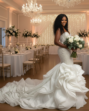 Luxurious strapless mermaid wedding dress featuring a deep sweetheart neckline, intricate beaded lace bodice, and a dramatic cascading ruffled train in elegant ivory satin.