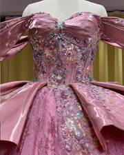 Sparkling pink quinceañera ball gown with off-shoulder sleeves, satin peplum, and glitter tulle skirt.