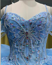 Sky blue quinceañera ball gown with glitter tulle, beaded sleeves, and full princess skirt.