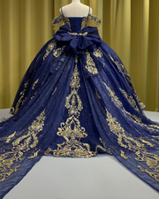 Navy blue off-shoulder quinceañera dress with gold appliqués, crystal embellishments, and full princess skirt.