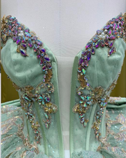 Mint green glitter quinceañera ball gown with rose gold appliqué and crystal corset bodice.