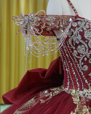 Burgundy Quinceañera dress with crystal tassels, spaghetti straps and corset bodice