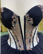 Black quinceañera dress with gold sequin appliqués, fitted bodice, and full princess skirt.