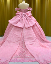 Baby pink quinceañera gown with glitter details, lace trim, and full princess ball skirt.