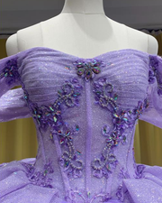 Lilac glitter quinceañera ball gown with layered ruffles and sparkling tulle.